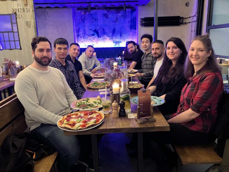 Gruppenfoto einiger NETSYNO-Teammitglieder aus Deutschland, Bulgarien und Uzbekistan am Esstisch im Restaurant